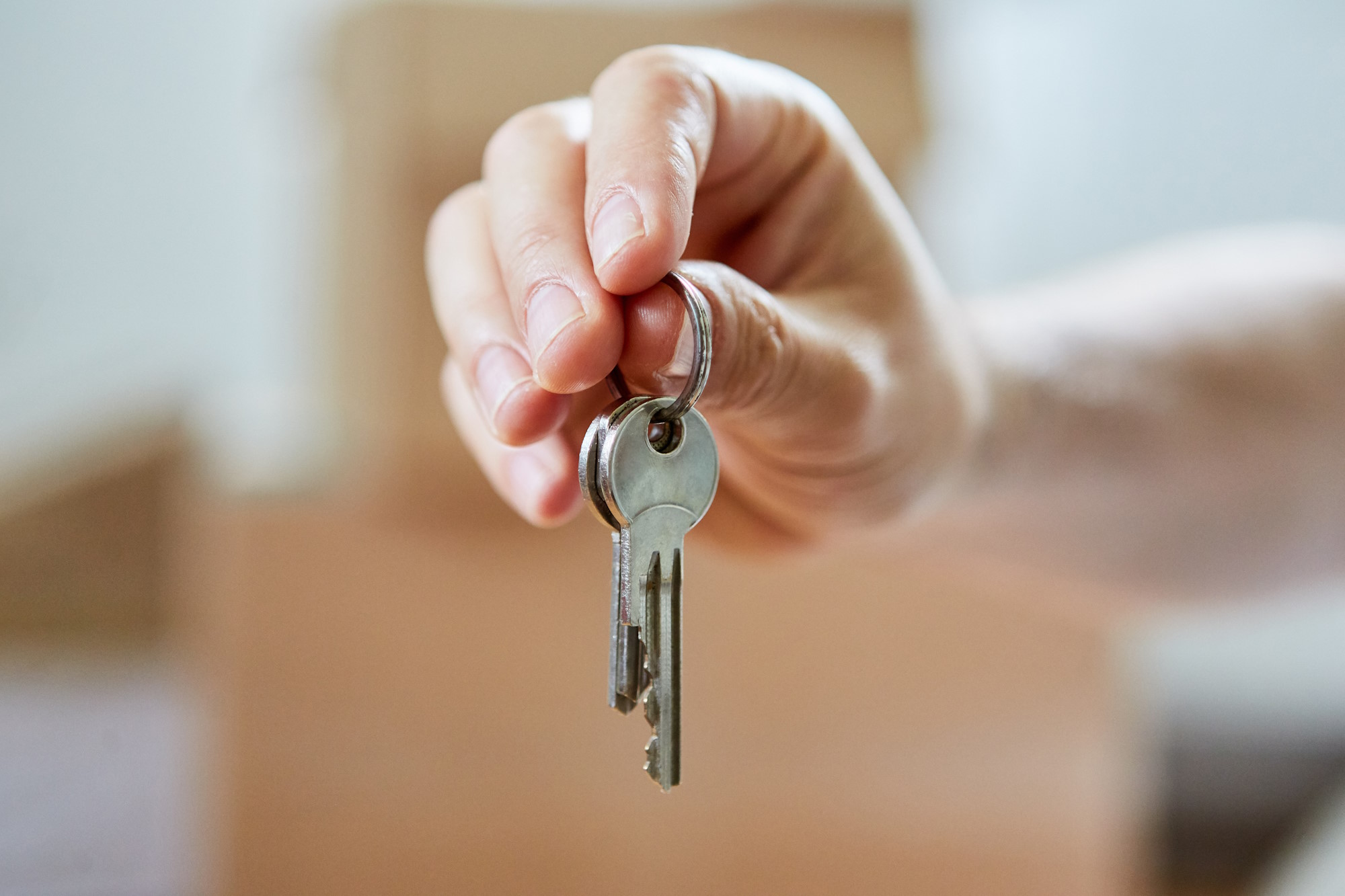 Eine Hand hält zwei Schlüssel an einem Ring in Nahaufnahme.
