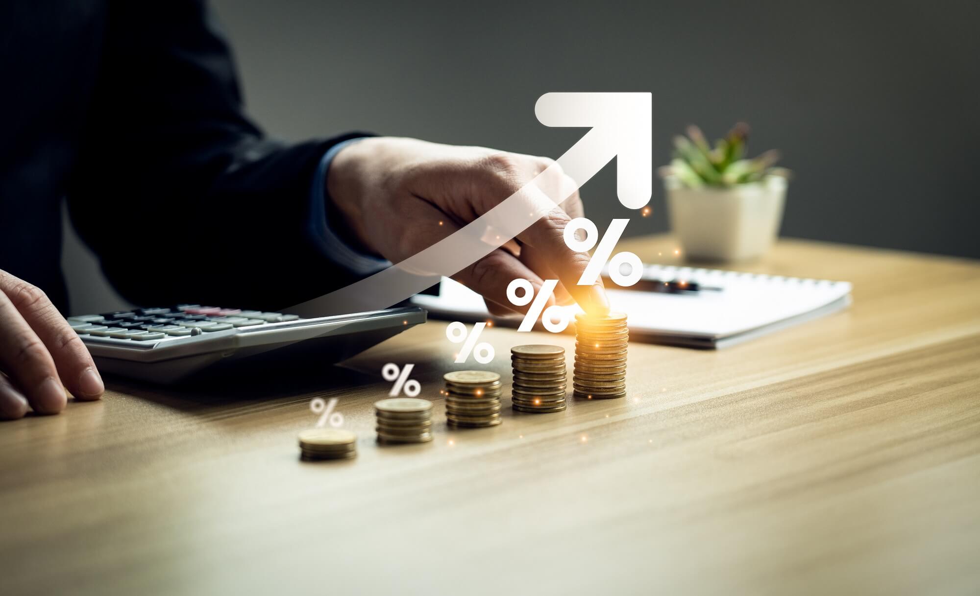 Ein Mann nutzt einen Taschenrechner. Stapel Münzen und ein aufsteigender Pfeil symbolisieren Wachstum.