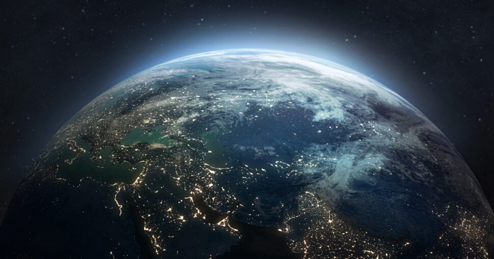 Erdansicht aus dem All mit beleuchteten Städten und hellem Horizont im Dunkel des Weltraums.